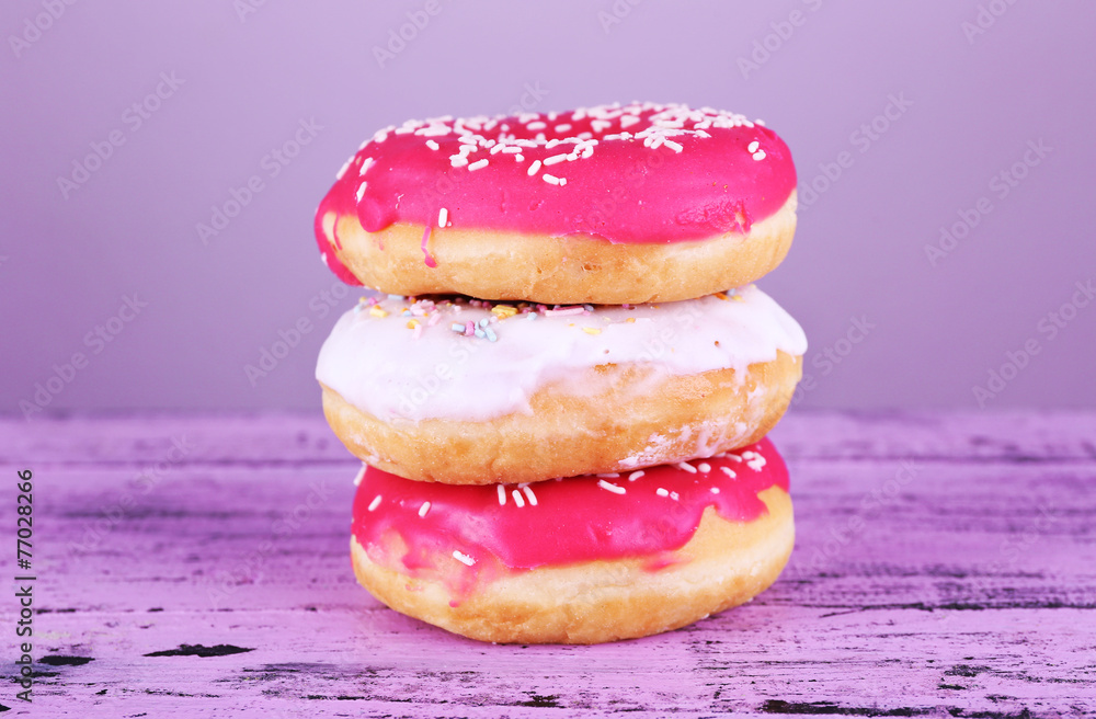 Delicious donuts with icing on table on bright background