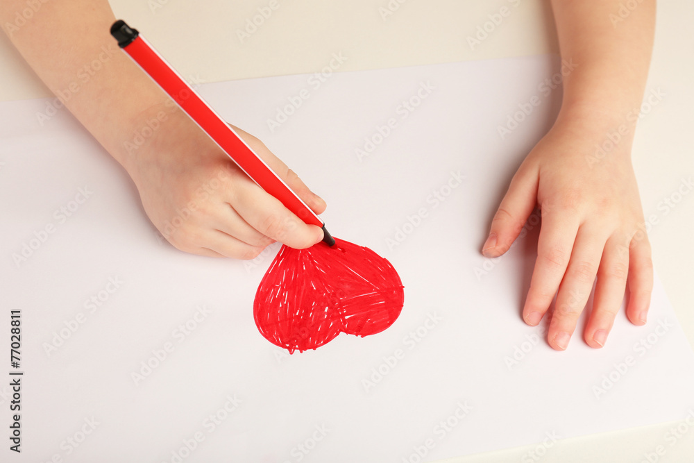 Close-up of child hands drawing a red heart
