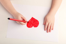 Close-up Of Child Hands Drawing A Red Heart