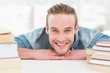© WavebreakMediaMicro - Smiling casual businessman with books at his desk