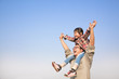 © Tom Wang - Father carrying his daughter on shoulders with blue sky backgrou