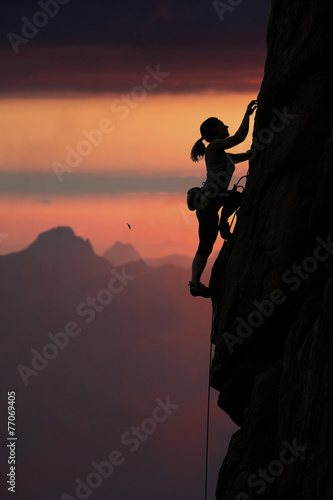 Plakat na zamówienie Elegant female alpine climber ascents rock against sunset