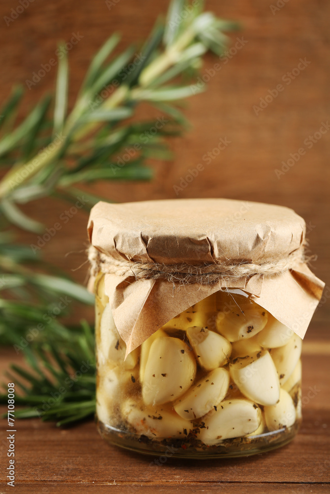 Canned garlic in glass jar on wooden background