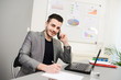 © W PRODUCTION - young man in office working with laptop computer and phone