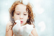 Happy little girl blowing foam with her hand.