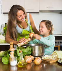 Woman with baby cooking at kitchen