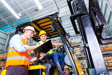 Asian forklift truck driver and foreman in storage