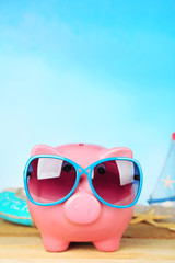 Poster - Piggy bank with sunglasses on wooden table, outdoors