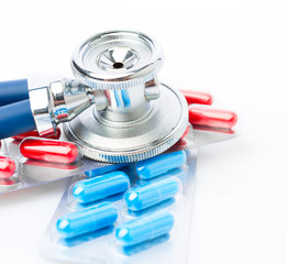 Stethoscope and some pills - isolated on a white background