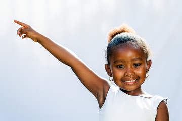 Wall Mural - African girl pointing at corner with finger.