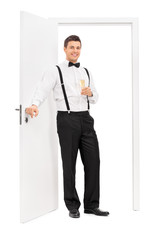 Wall Mural - Elegant guy standing by a door and holding wine