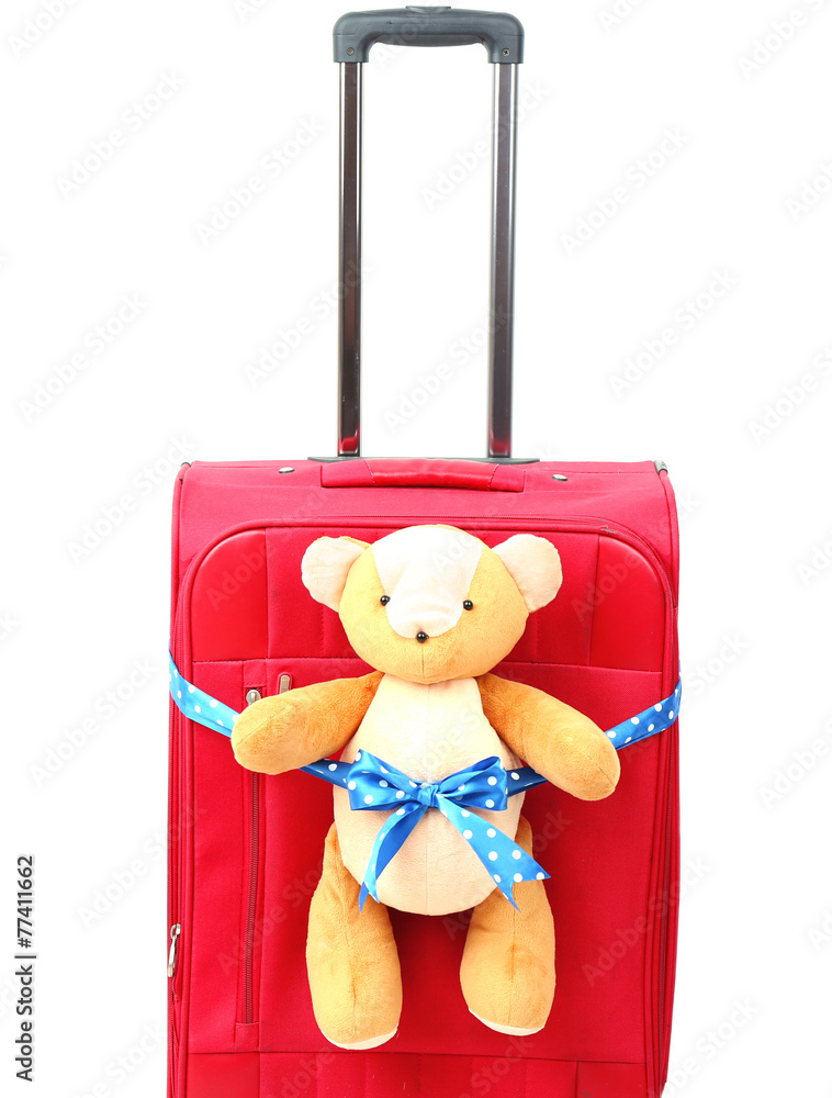 Red suitcase with toy teddy bear isolated on white