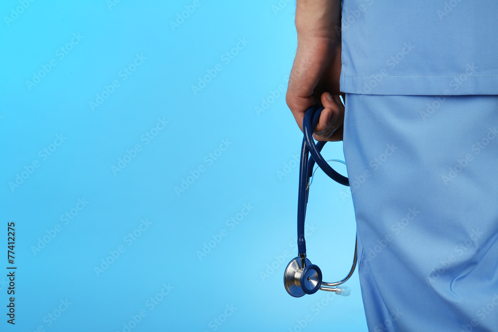 Male doctor with stethoscope on blue background