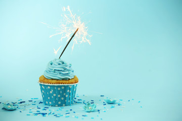 Wall Mural - Cupcake with sparkler on blue background