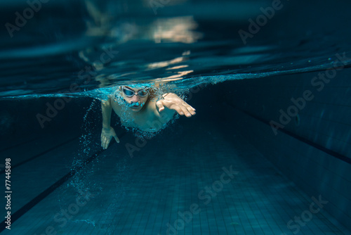 Plakat Mężczyzna pływaczka przy pływackim basenem. Podwodna fotografia.