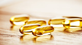Fototapeta Uliczki - Fish oil omega 3 gel capsules  on wooden background