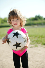 little girl plays football on stadium