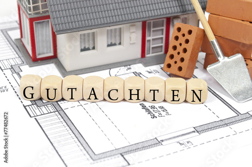 Foto Bauplan mit Ziegelstein und Haus mit Gutachten