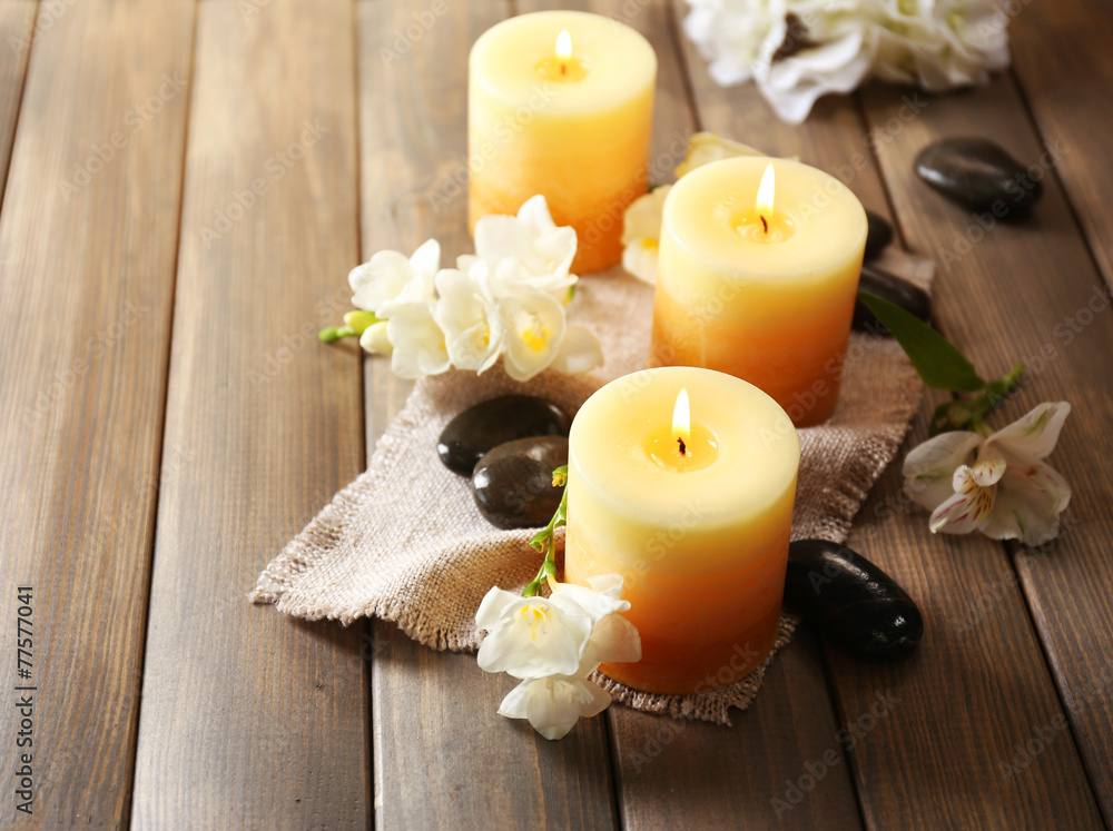 Beautiful candles with flowers on wooden background