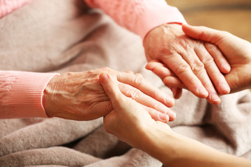 Wall Mural - Old and young holding hands on light background