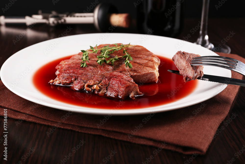 Grilled steak in wine sauce on plate on table close up