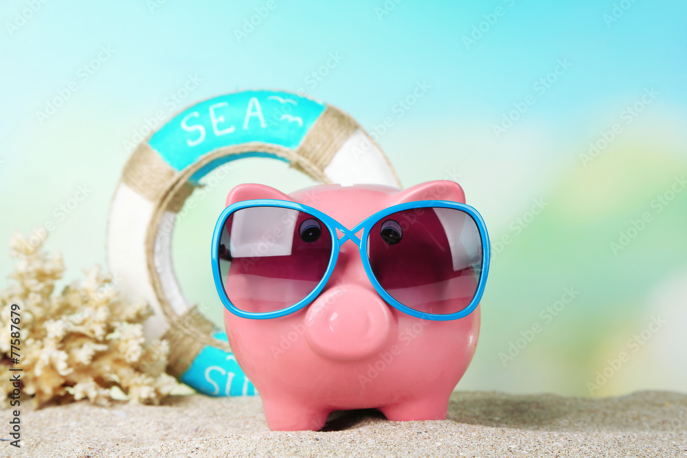 Piggy bank with sunglasses on the beach