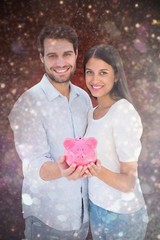 Poster - Composite image of happy couple showing their piggy bank