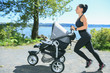 © Louis-Photo - A Young mother jogging with a baby buggy