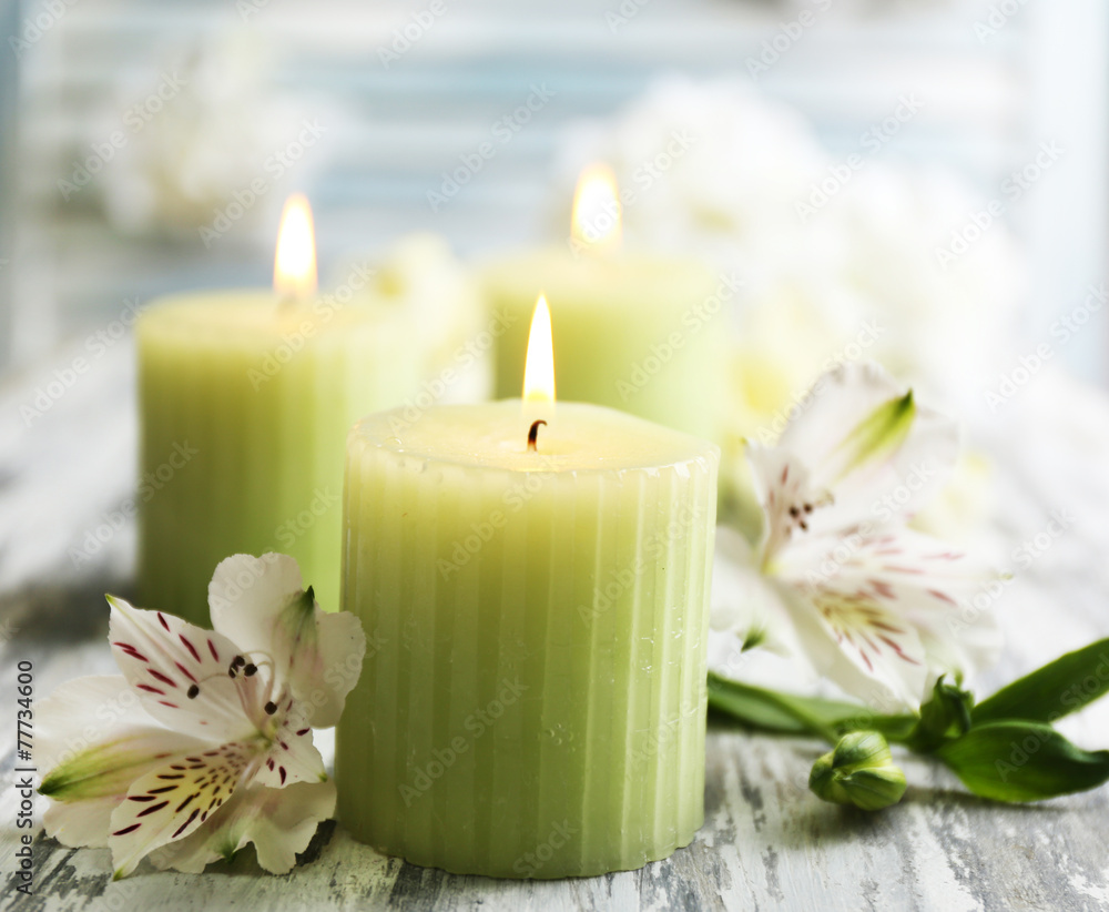 Beautiful candles with flowers on wooden background