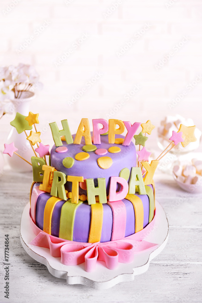Delicious birthday cake on table on brick wall background
