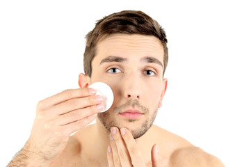 Handsome young man cleansing face isolated on white