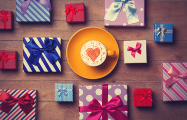 Cup and gift boxes on wooden background