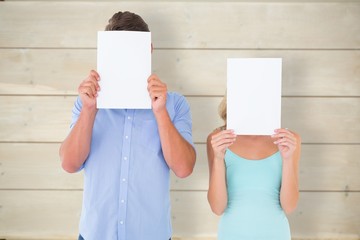Poster - Composite image of young couple holding pages over their faces