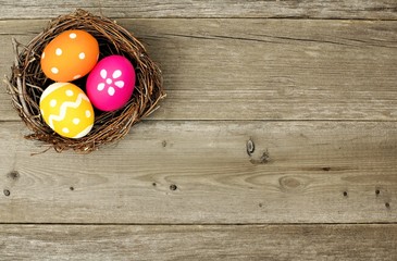 Easter eggs in a nest over an old wood background