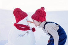 Happy Beautiful Child Building Snowman In Garden,nose To Nose