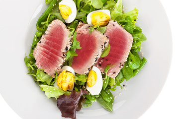 Poster - Delicious tuna steak with fresh green salad on white plate.