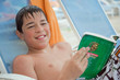 Jeune ado lisant au bord de la piscine
