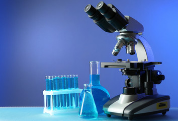 Wall Mural - Microscope and test tubes on table, on color background