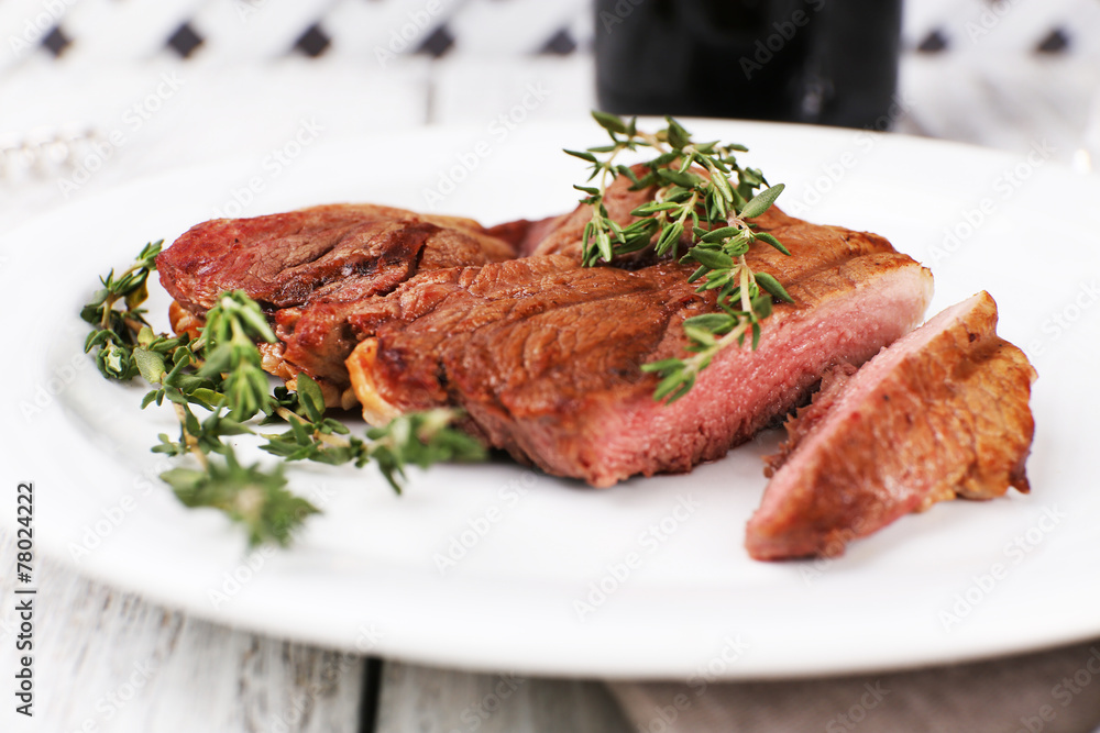 Steak with herbs on plate on wooden table