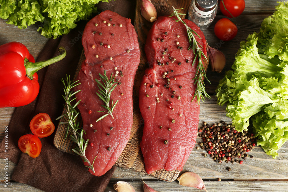 Raw beef steak with spices and greens on table close up
