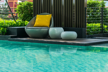 Relaxing chairs with pillows beside swimming pool