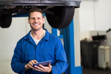 Wall Mural - Smiling mechanic looking at camera using tablet