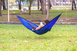 © CasanoWa Stutio - man lying on hammock in garden with tablet computer.