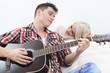 © Louis-Paul Photo - A handsome man playing guitar to a cute girl
