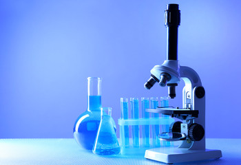 Wall Mural - microscope and test tubes on table, on color background