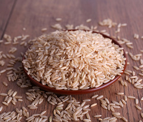 Poster - Brown rice on plate on wooden background