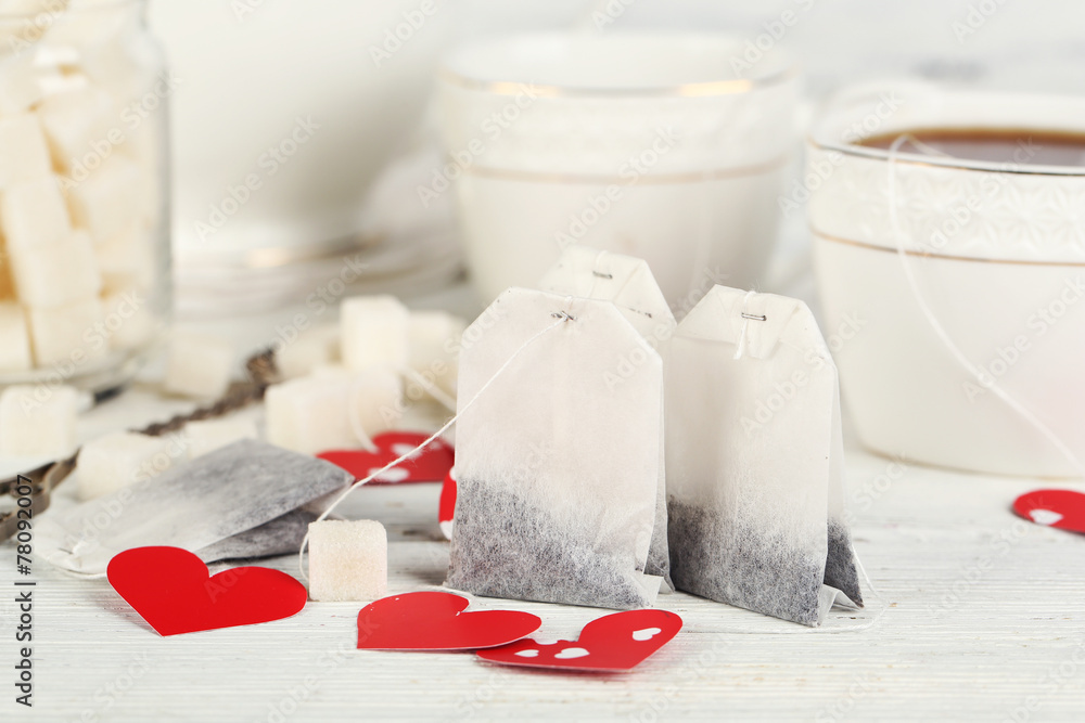 Heart shaped teabag tags, box and teapot on wooden background