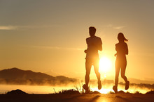 Silhouette Of A Couple Running At Sunset