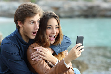 Sticker - Shocked couple watching a smart phone on holidays