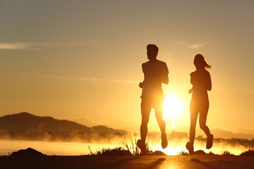 Silhouette of a couple running at sunset